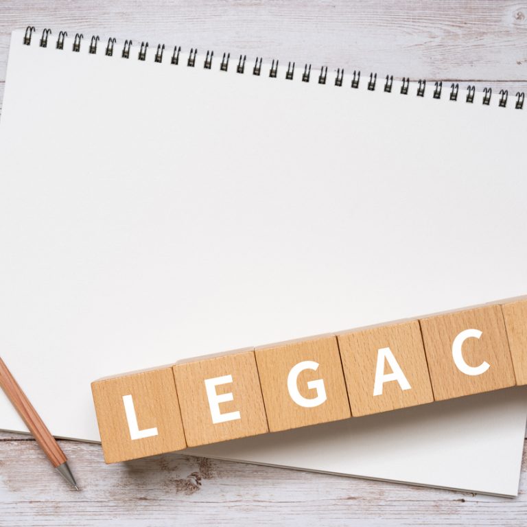 Wooden blocks with "LEGACY" text of concept, a pen, and a notebook.