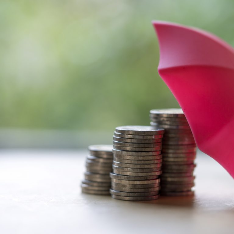 Red umbrella and the stack of coins. Keeping money safe. savings protection, Investment and capital insurance concept. Security by insurance concept. Risk management.